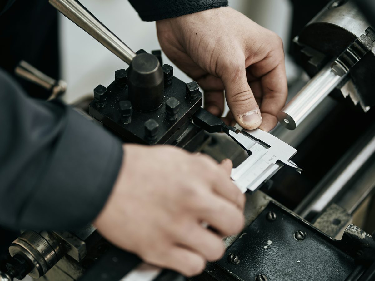 Mitarbeiter misst Metallwerkstück mit Messschieber
