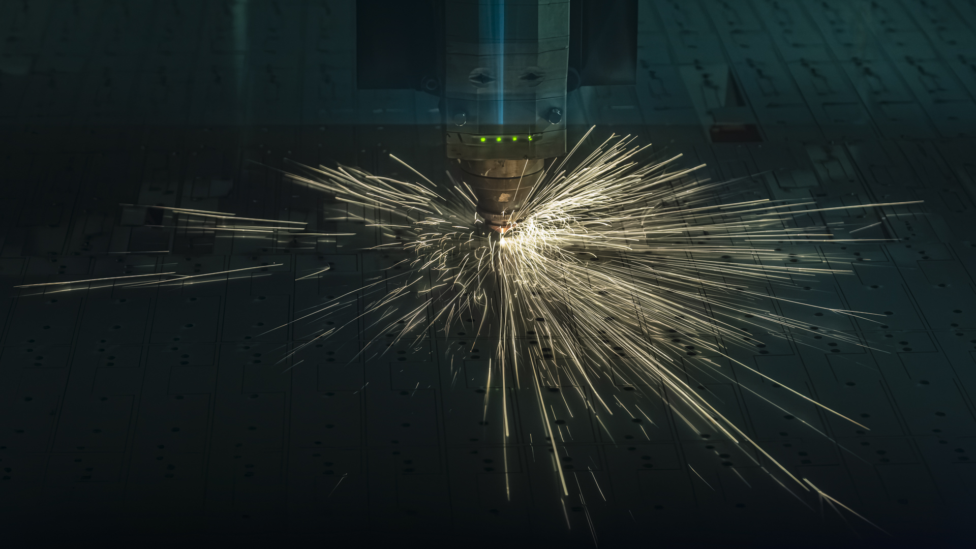 Laserschneidkopf in Aktion mit Funkenflug auf Stahlblech